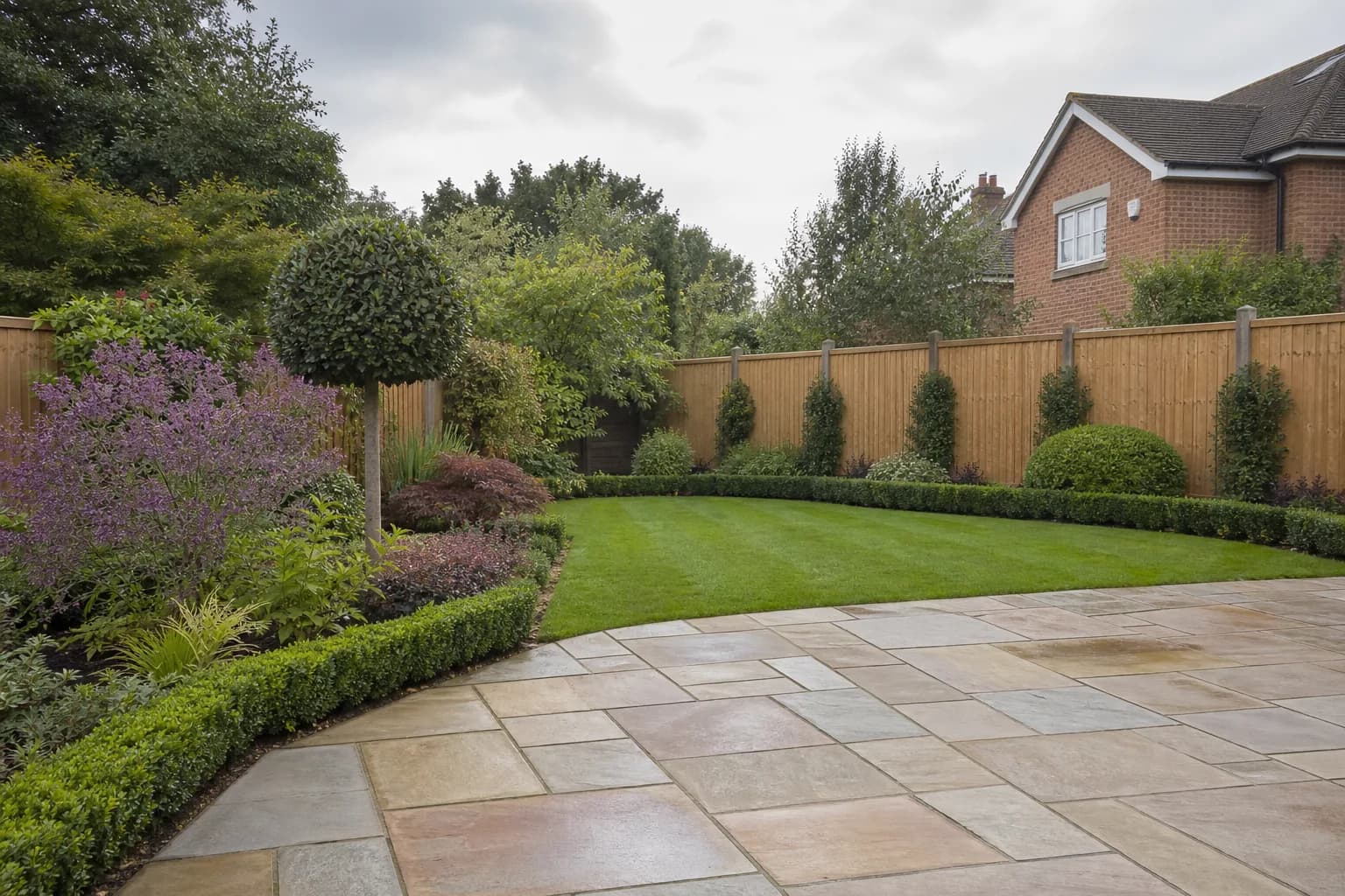 Tidy maintained garden with trimmed hedges, a swept patio and a timber fence